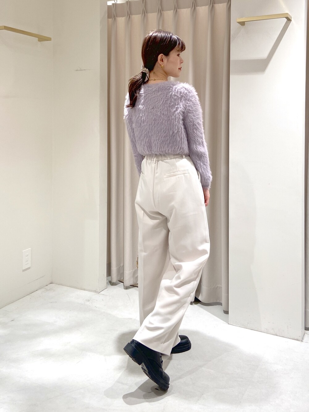 パープル系のカーディガン/ボレロ、ホワイト系のスラックス、ベージュ系のショルダーバッグを着用したレディースの秋コーディネートの3枚目の写真