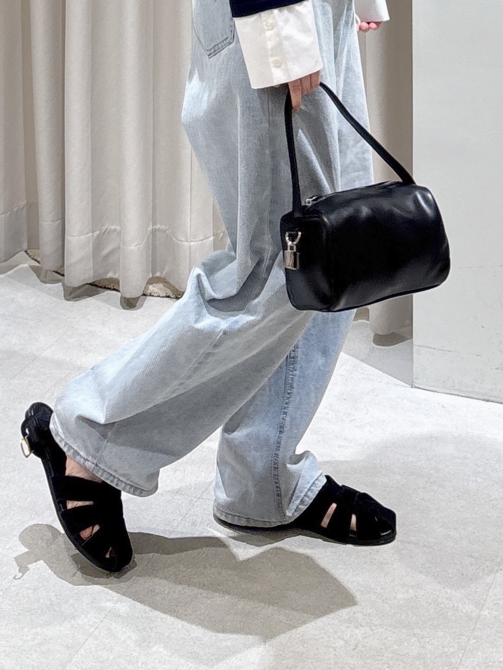 ブルー系のTシャツ/カットソー、ブラック系のハンドバッグ、ブルー系のデニムパンツを着用したレディースの春コーディネートの6枚目の写真