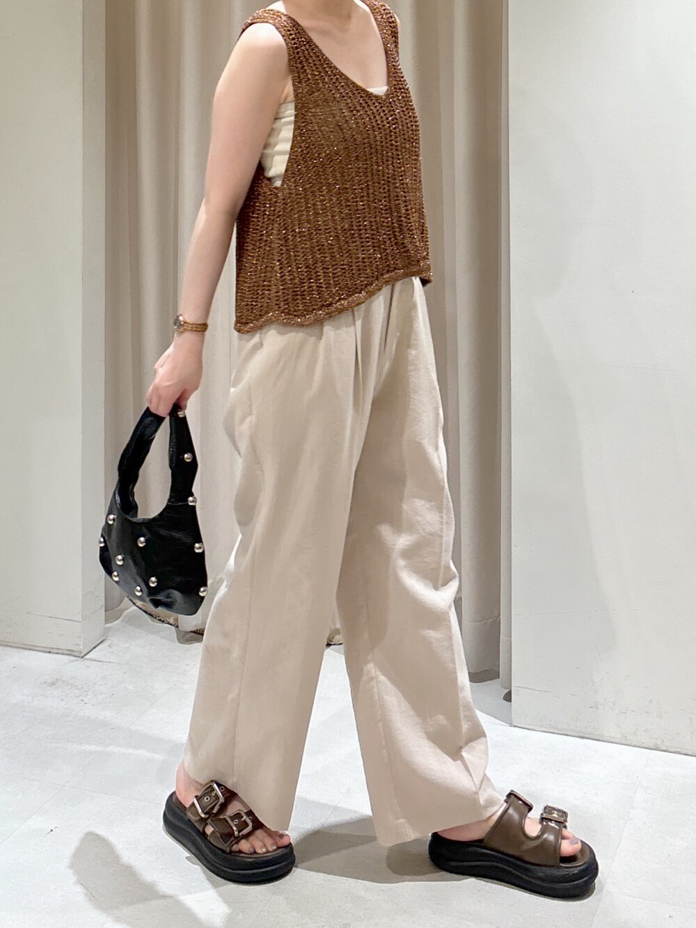 ブラウン系のベスト、ホワイト系のキャミソール、ブラック系のハンドバッグを着用したレディースの夏コーディネートの4枚目の写真