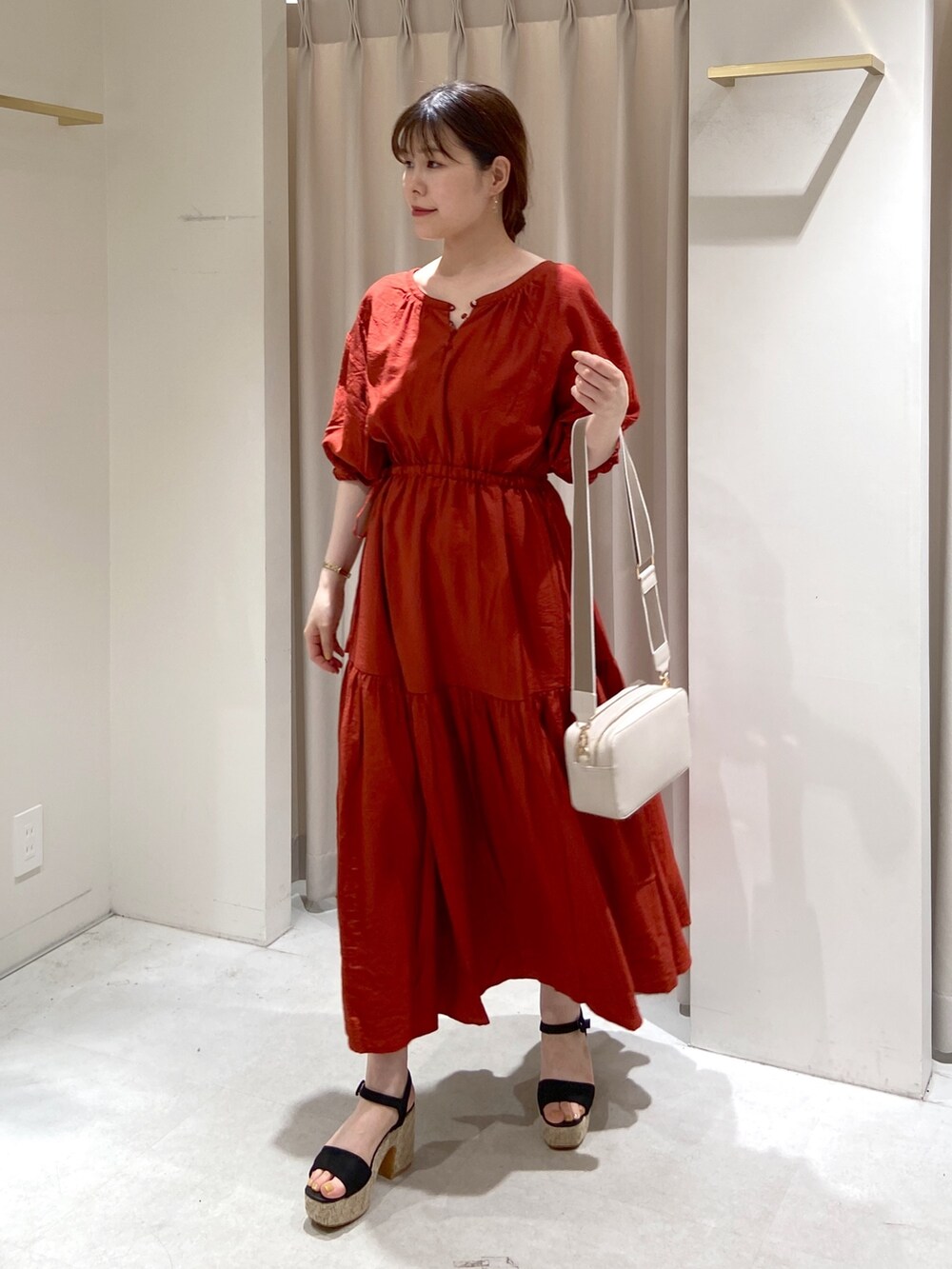 レッド系のワンピース、ホワイト系のボディバッグ/ウエストポーチ、ブラック系のサンダルを着用したレディースの春コーディネートの2枚目の写真