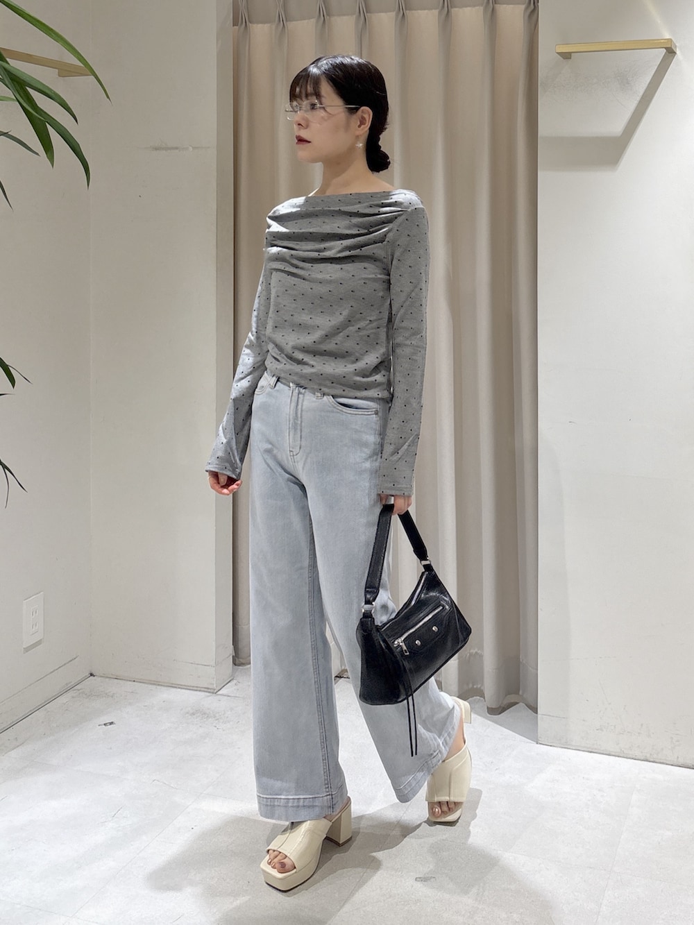 ブルー系のデニムパンツ、ブラック系のショルダーバッグ、ホワイト系のサンダルを着用したレディースの夏コーディネートの3枚目の写真