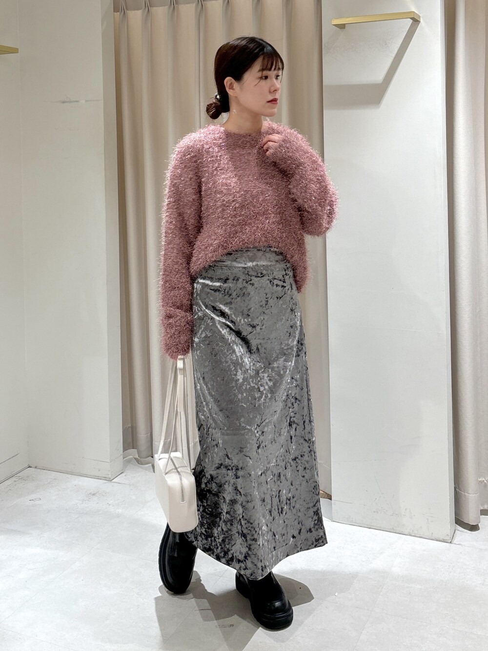 グレー系のステンカラーコート、ホワイト系のショルダーバッグ、ブラック系のブーツを着用したレディースの冬コーディネートの5枚目の写真