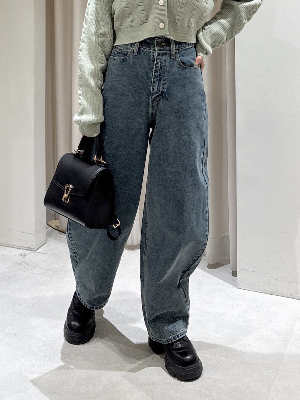 グリーン系のワンピース、ブルー系のデニムパンツ、ブラック系のトートバッグを着用したレディースの冬コーディネートの4枚目の写真