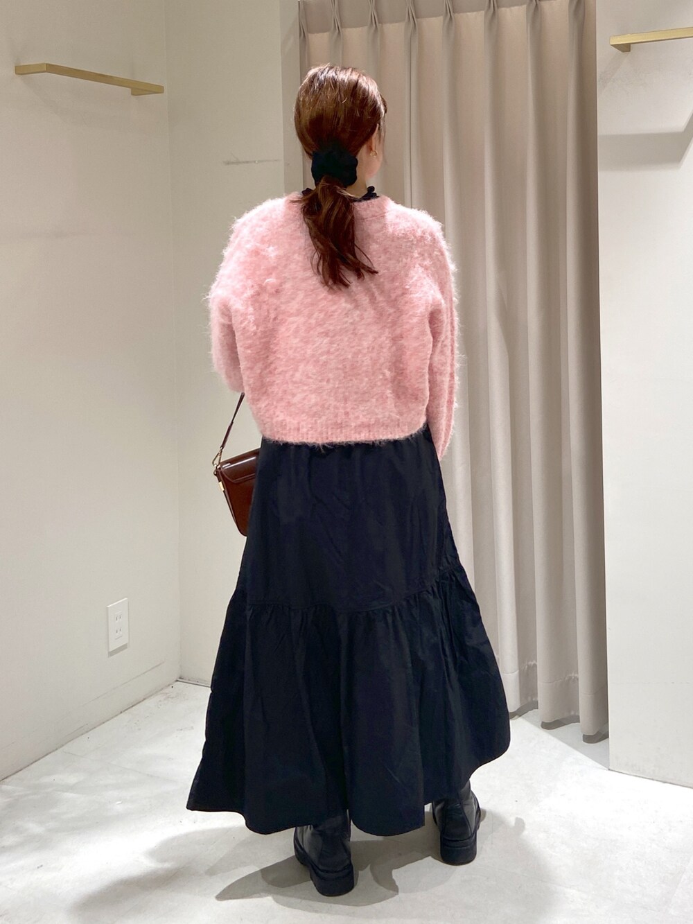 ブラック系のスカート、ブラウン系のショルダーバッグ、ブラック系のブーツを着用したレディースの冬コーディネートの4枚目の写真