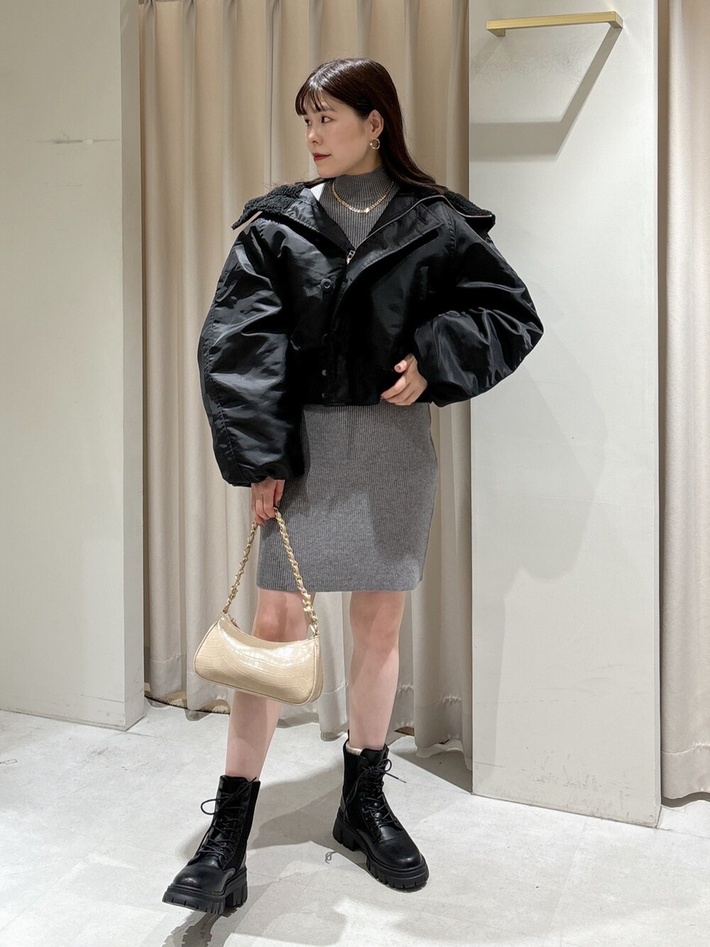 グレー系のワンピース、ベージュ系のトートバッグ、ブラック系のブーツを着用したレディースの秋コーディネートの2枚目の写真