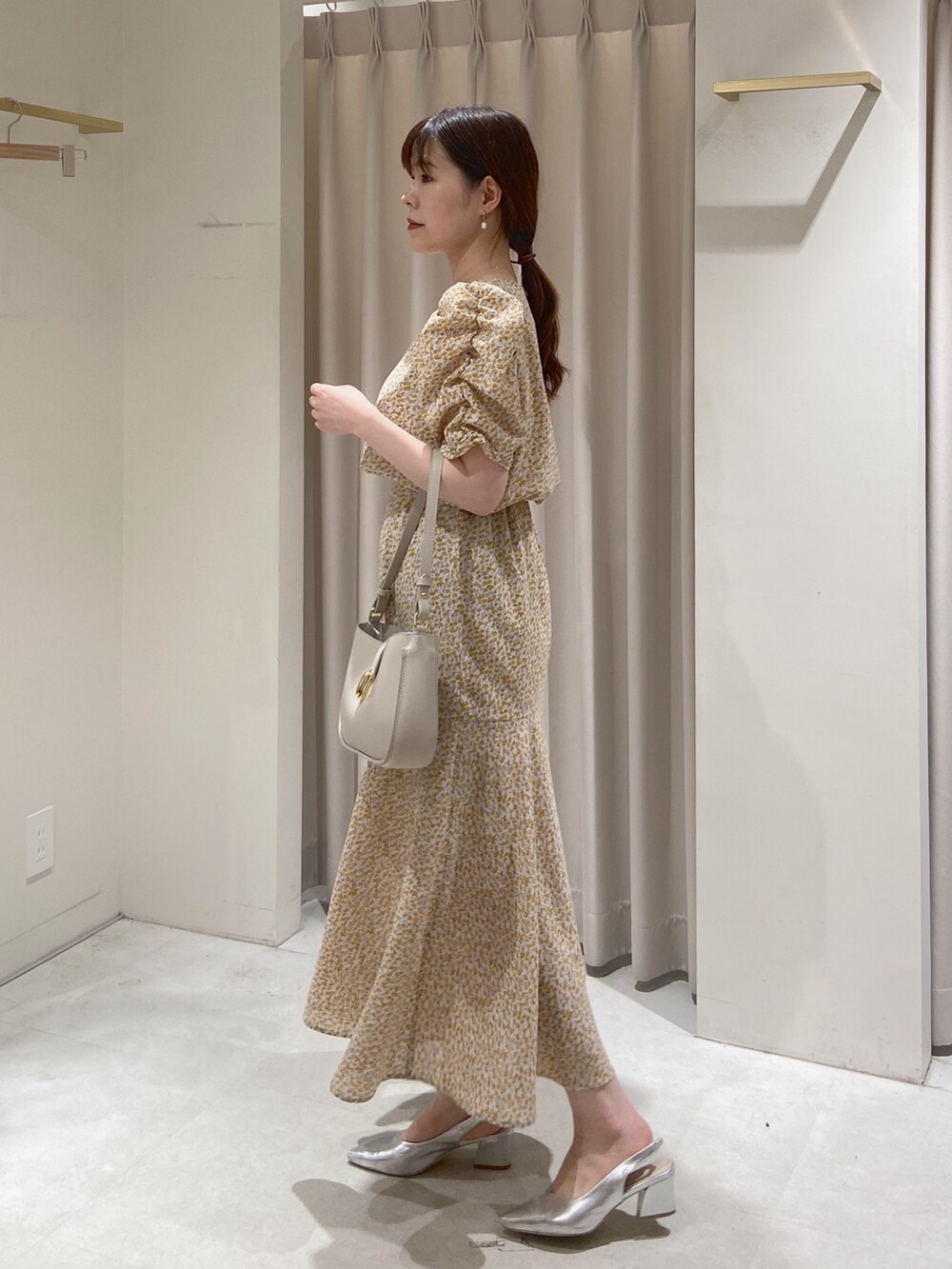 イエロー系のワンピース、グレー系のショルダーバッグ、シルバー系のパンプスを着用したレディースの春コーディネートの3枚目の写真