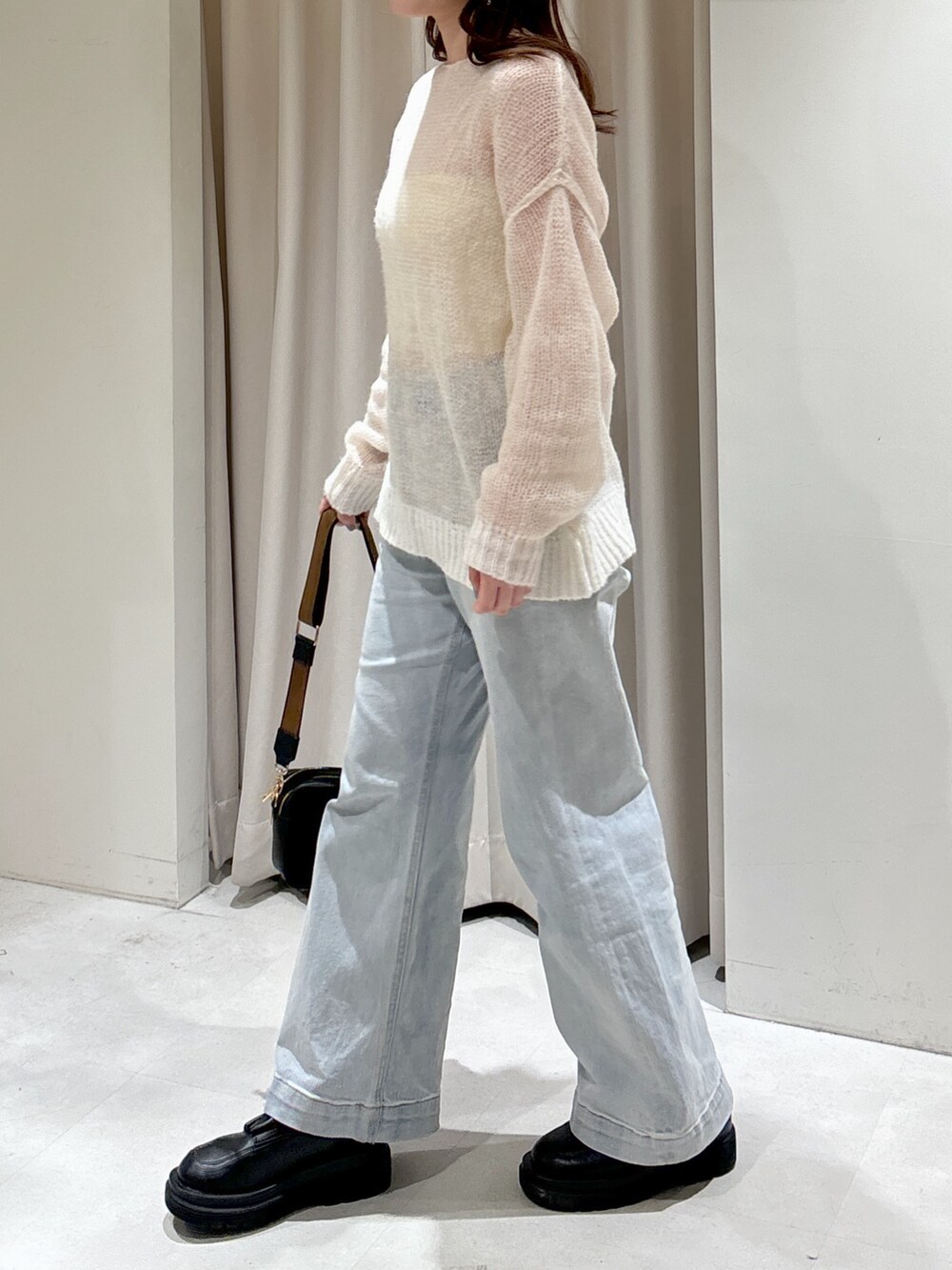 ホワイト系のニット/セーター、ブラック系のショルダーバッグ、ブルー系のデニムパンツを着用したレディースの冬コーディネートの2枚目の写真