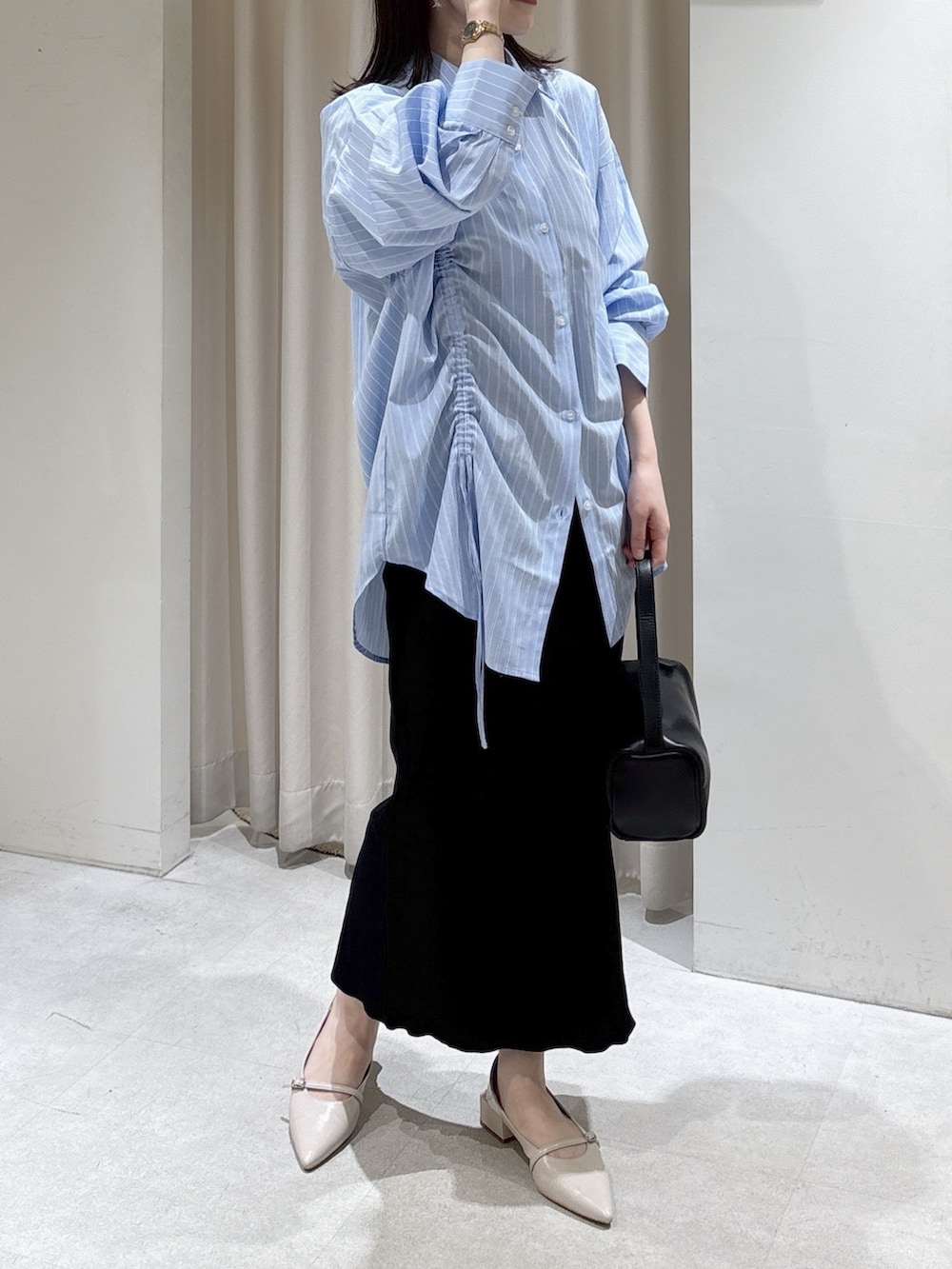 ブルー系のシャツ/ブラウス、ブラック系のハンドバッグ、ブラック系のスカートを着用したレディースの春コーディネートの6枚目の写真