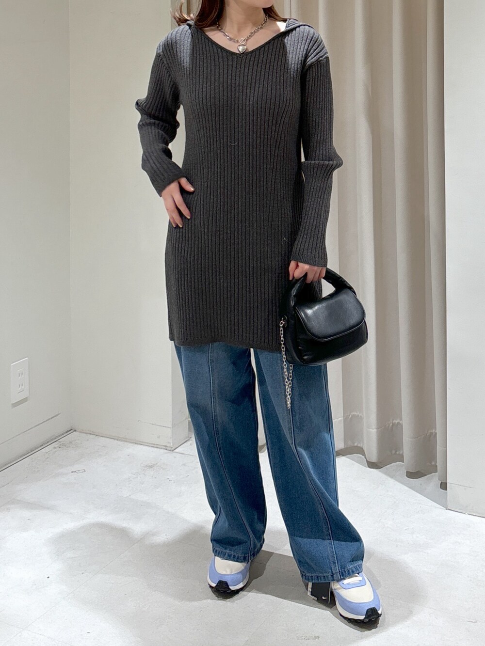 グレー系のワンピース、ブラック系のショルダーバッグ、ブルー系のデニムパンツを着用したレディースの冬コーディネートの2枚目の写真