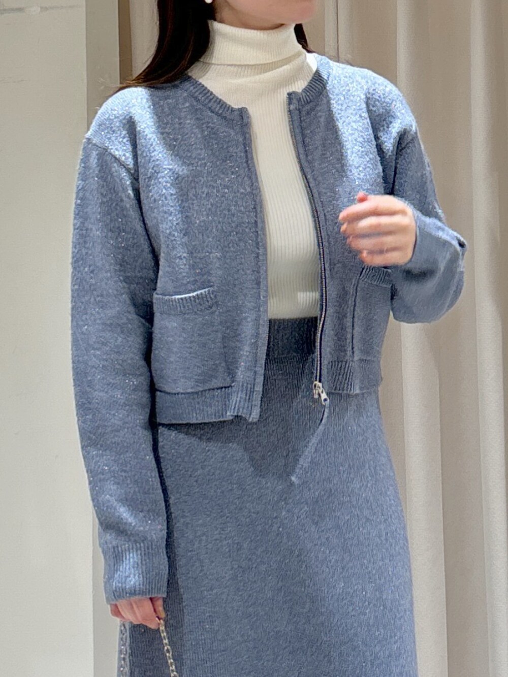 ブルー系のワンピース、ホワイト系のニット/セーター、ブラック系のショルダーバッグを着用したレディースの冬コーディネートの3枚目の写真