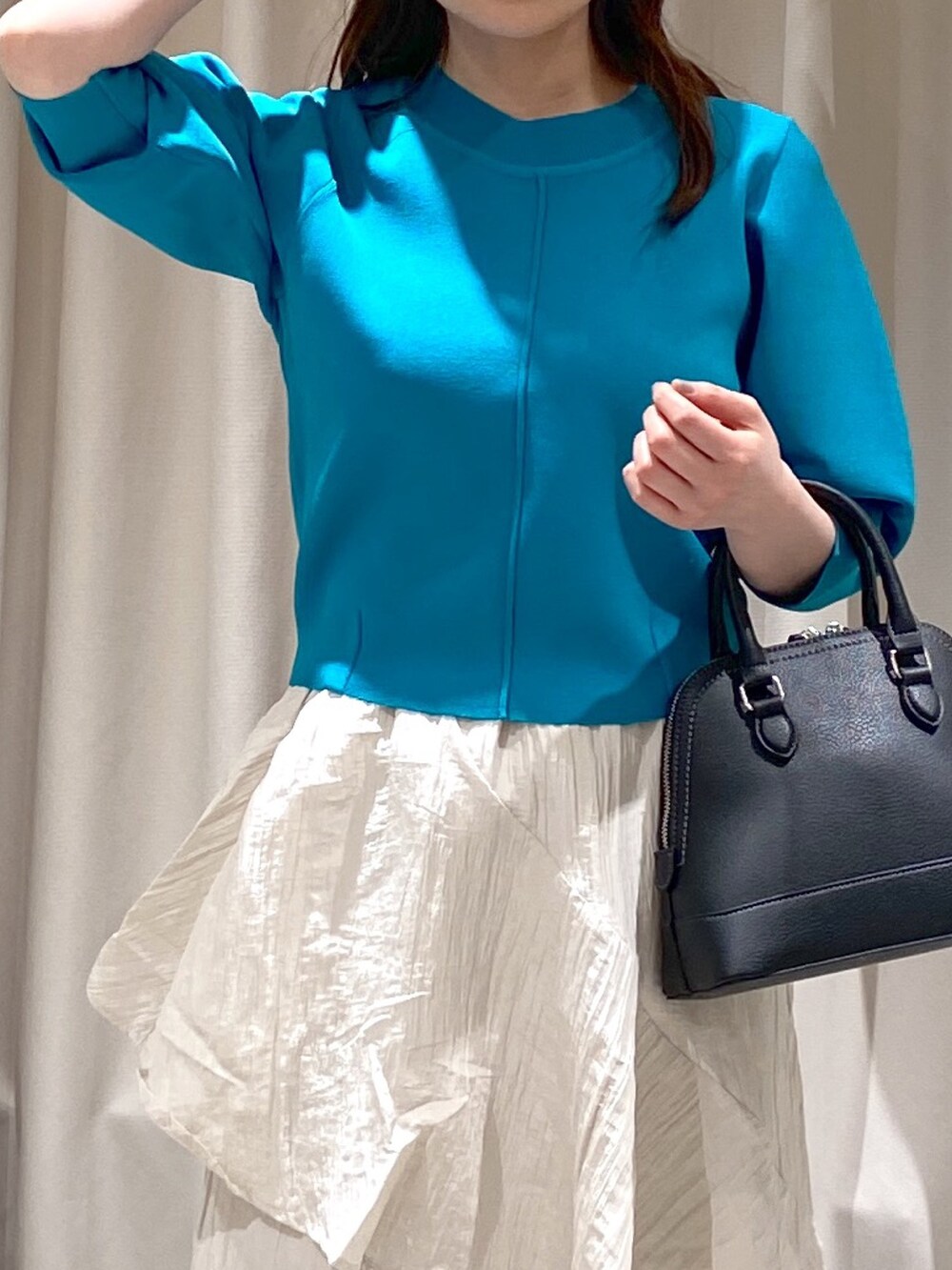 ブルー系のニット/セーター、ホワイト系のスカート、ブラック系のショルダーバッグを着用したレディースの冬コーディネートの2枚目の写真