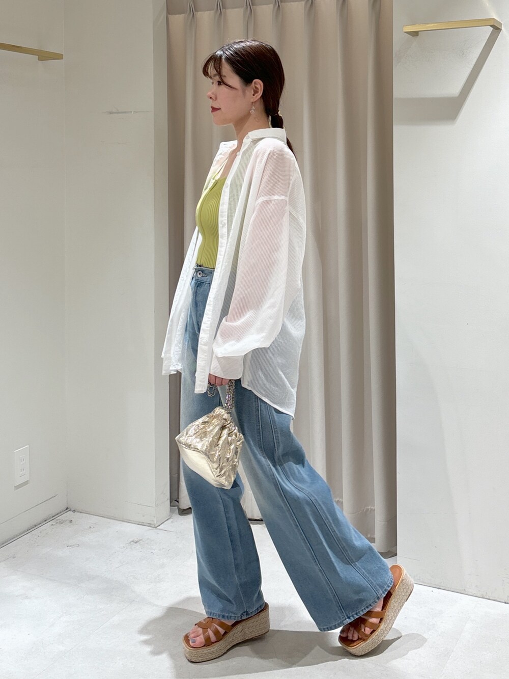 グリーン系のニット/セーター、ブルー系のデニムパンツ、ホワイト系のシャツ/ブラウスを着用したレディースの夏コーディネートの6枚目の写真