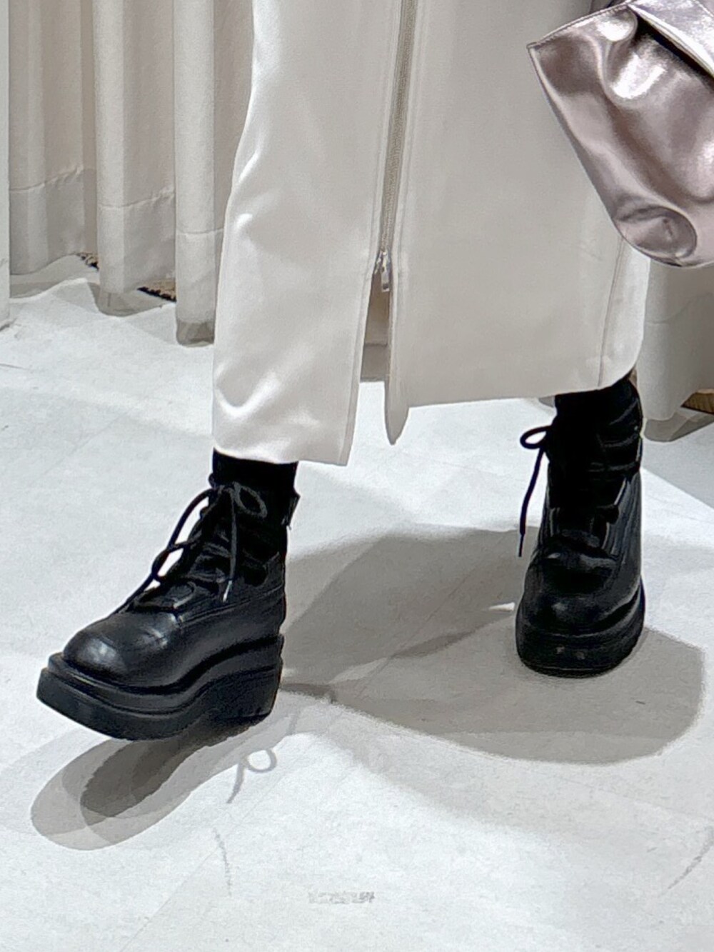 ホワイト系のニット/セーター、グレー系のスカート、シルバー系のハンドバッグを着用したレディースの冬コーディネートの6枚目の写真