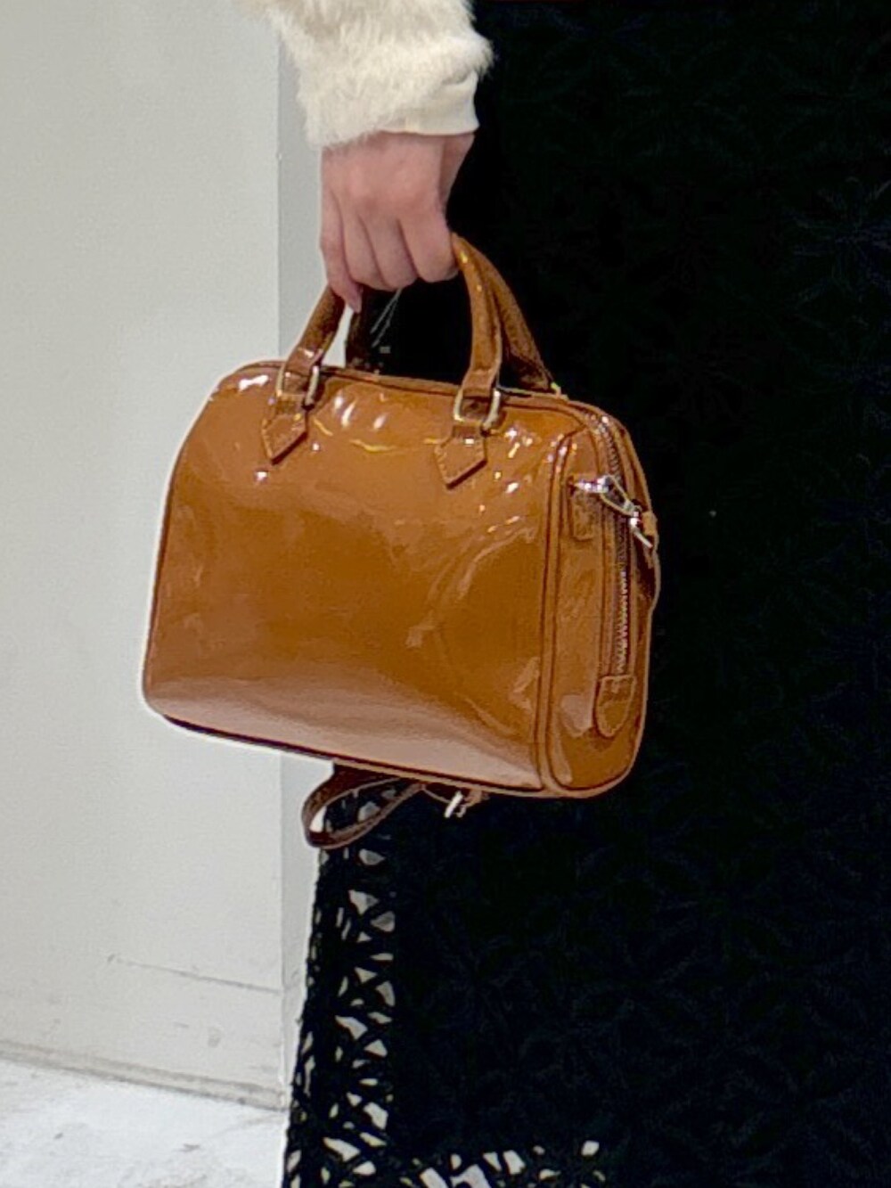 ブラック系のスカート、ベージュ系のショルダーバッグ、ブラック系のブーツを着用したレディースの冬コーディネートの8枚目の写真