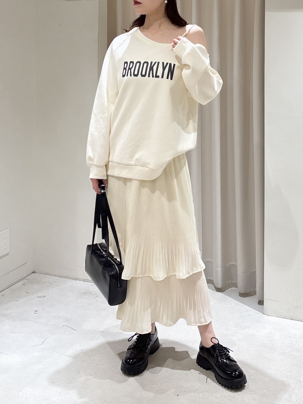 ホワイト系のスウェット、ホワイト系のスカート、ブラック系のショルダーバッグを着用したレディースの春コーディネートの2枚目の写真