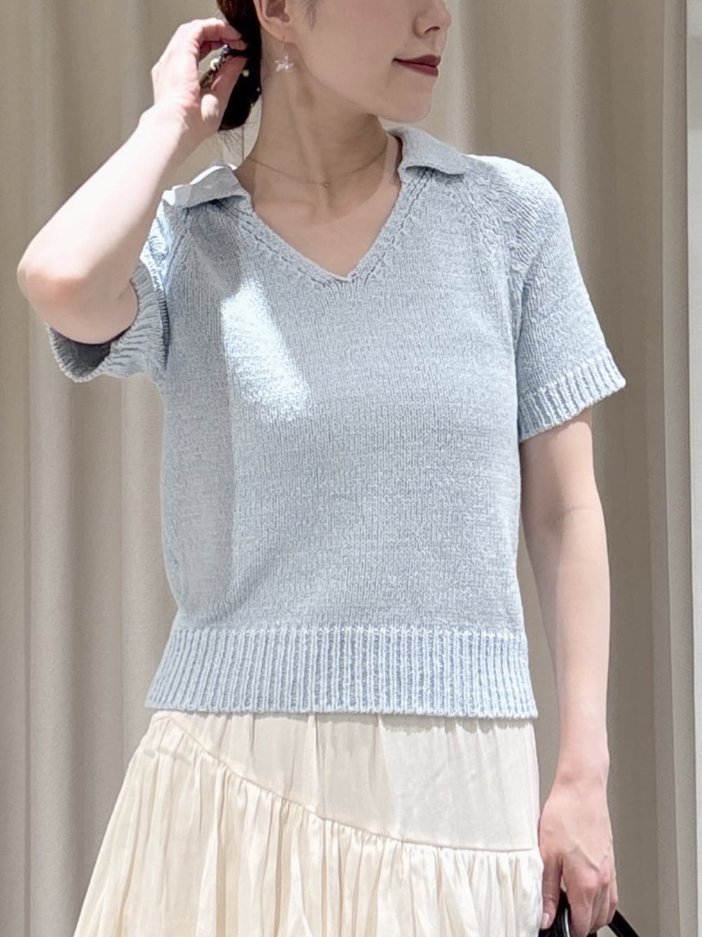 ブルー系のニット/セーター、ホワイト系のスカート、ブラック系のハンドバッグを着用したレディースの春コーディネートの2枚目の写真