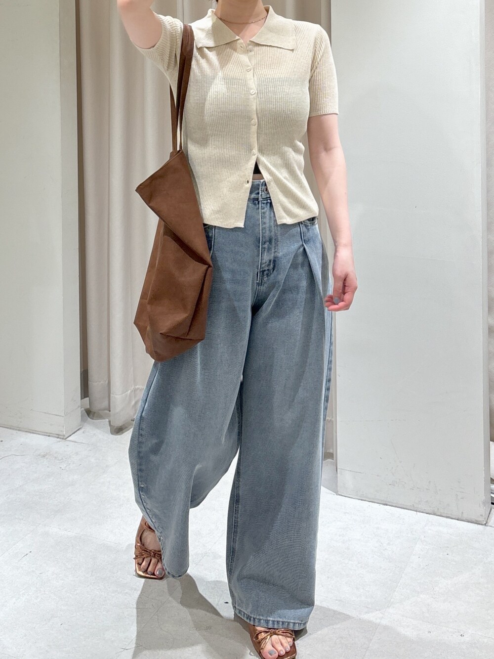 ブルー系のデニムパンツ、ブラウン系のサンダル、ブラック系のキャミソールを着用したレディースの春コーディネートの4枚目の写真