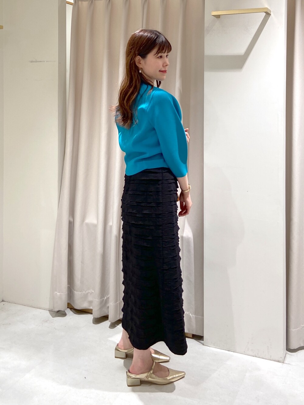 ブラック系のスカート、ブルー系のニット/セーター、ブラウン系のショルダーバッグを着用したレディースの春コーディネートの3枚目の写真