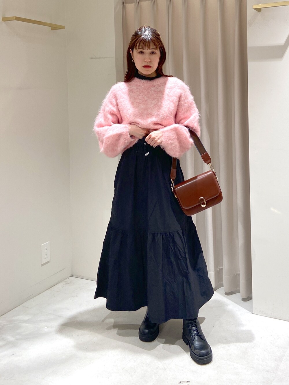 ブラック系のスカート、ブラウン系のショルダーバッグ、ブラック系のブーツを着用したレディースの冬コーディネートの2枚目の写真