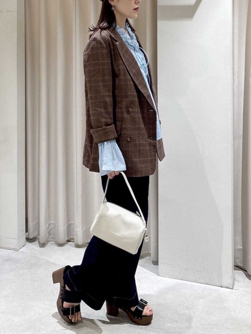 ブラウン系のテーラードジャケット、ホワイト系のハンドバッグ、ブルー系のデニムパンツを着用したレディースの春コーディネートの3枚目の写真