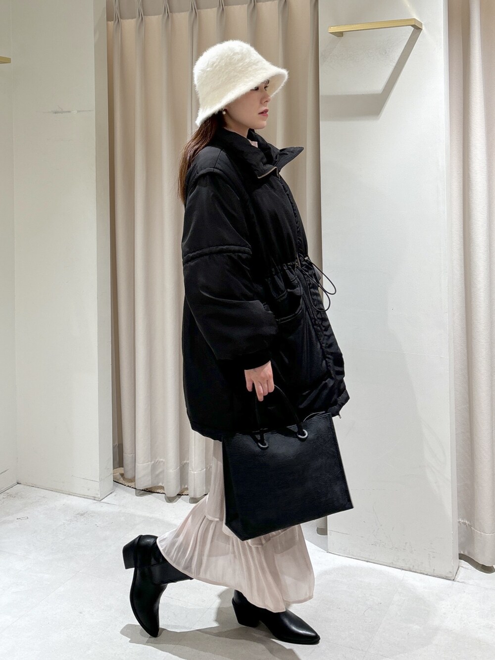 ブラック系のトートバッグ、ホワイト系のスカート、ブラック系のブーツを着用したレディースの冬コーディネートの7枚目の写真