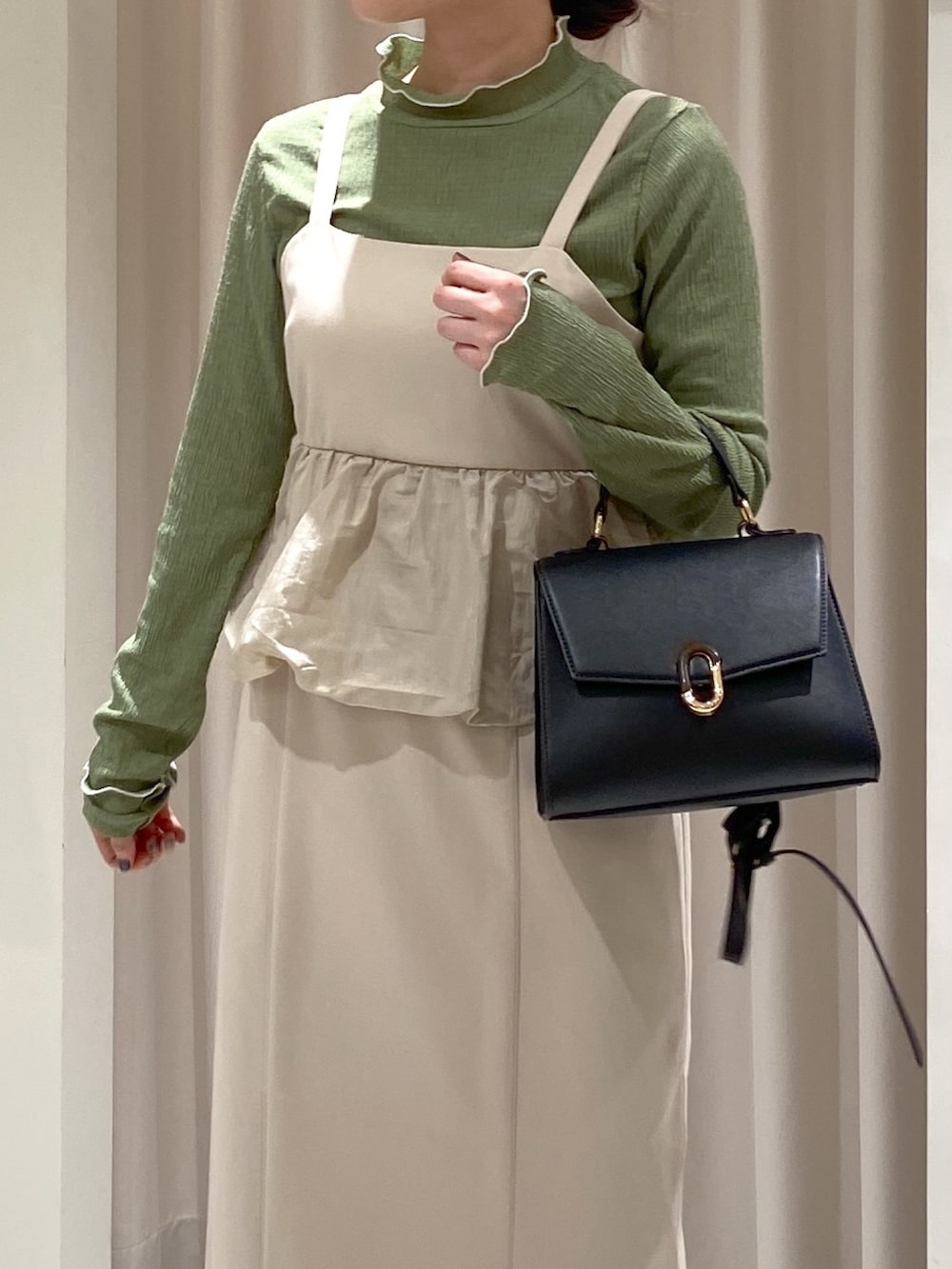 ホワイト系のワンピース、ブラック系のショルダーバッグ、グリーン系のTシャツ/カットソーを着用したレディースの冬コーディネートの2枚目の写真