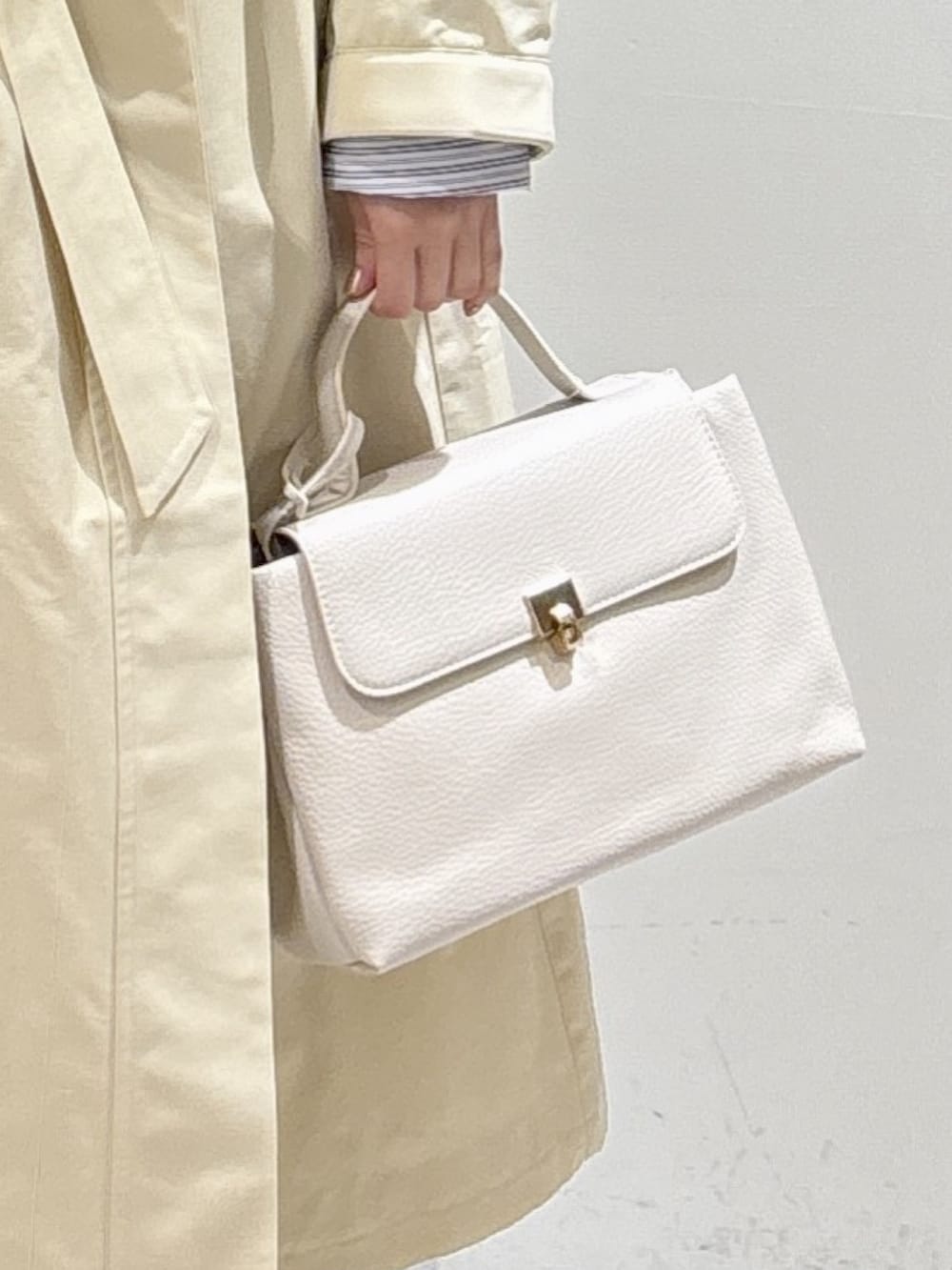 ホワイト系のトレンチコート、ベージュ系のニット/セーター、ブラック系のスニーカーを着用したレディースの冬コーディネートの10枚目の写真