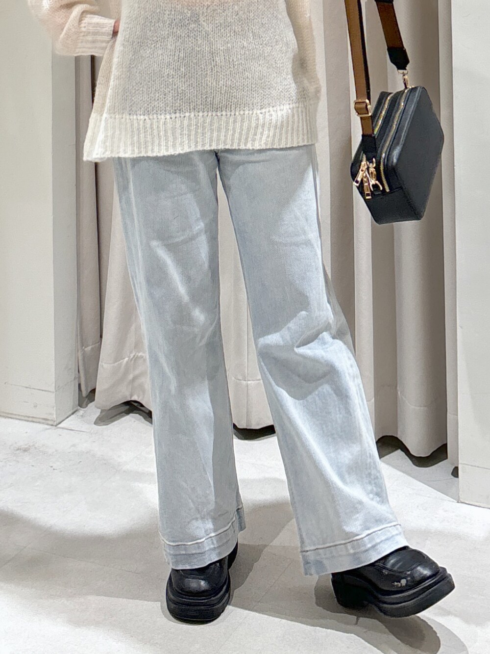 ホワイト系のニット/セーター、ブラック系のショルダーバッグ、ブルー系のデニムパンツを着用したレディースの冬コーディネートの3枚目の写真