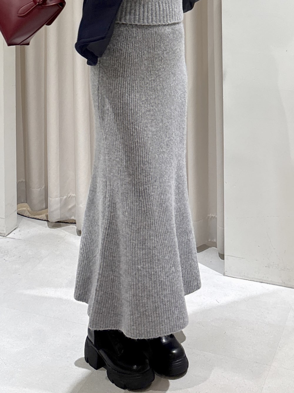 グレー系のワンピース、レッド系のショルダーバッグ、ブラック系のブーツを着用したレディースの秋コーディネートの4枚目の写真