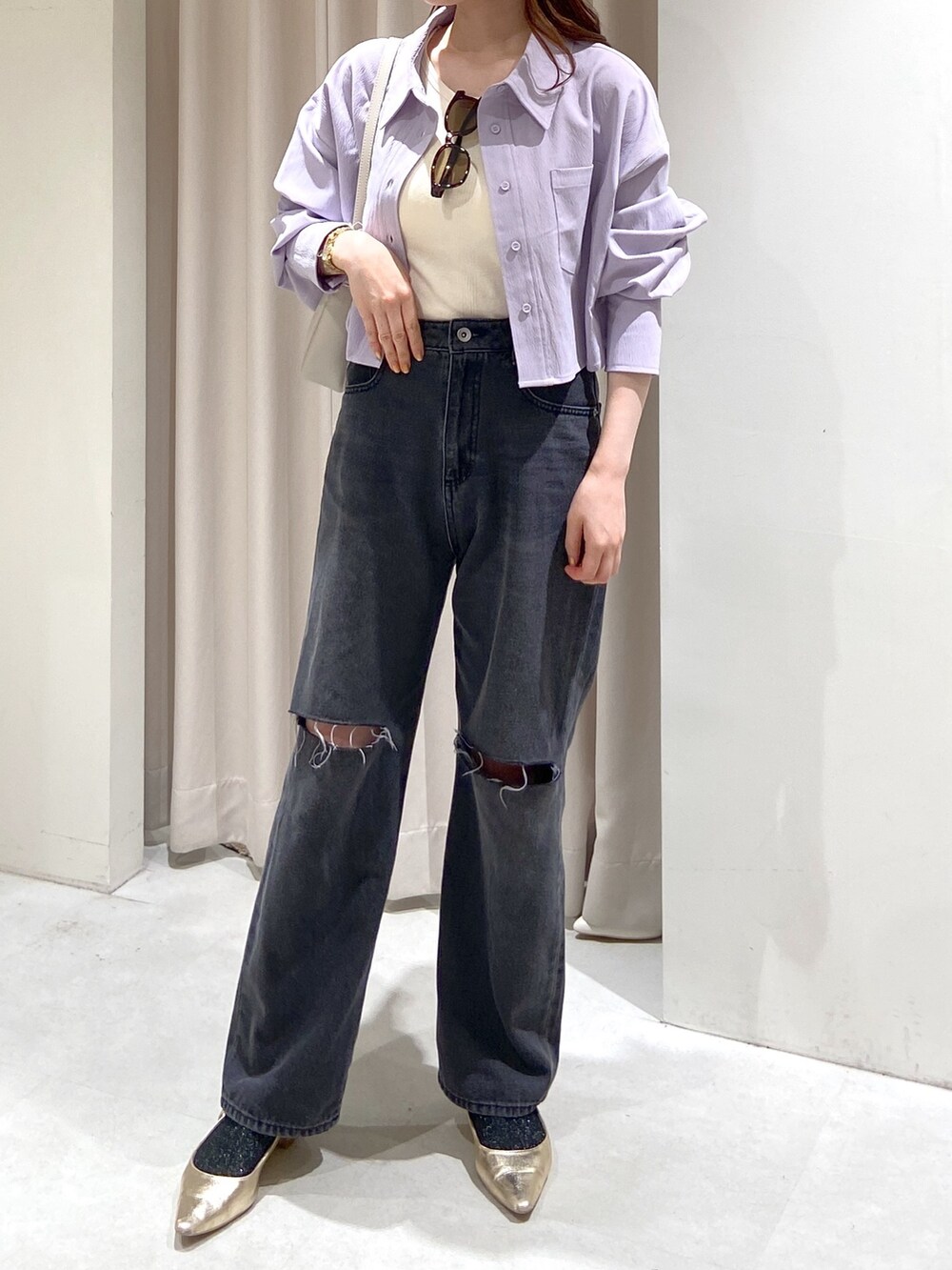 ブラック系のデニムパンツ、ゴールド系のパンプス、グレー系のショルダーバッグを着用したレディースの春コーディネートの3枚目の写真