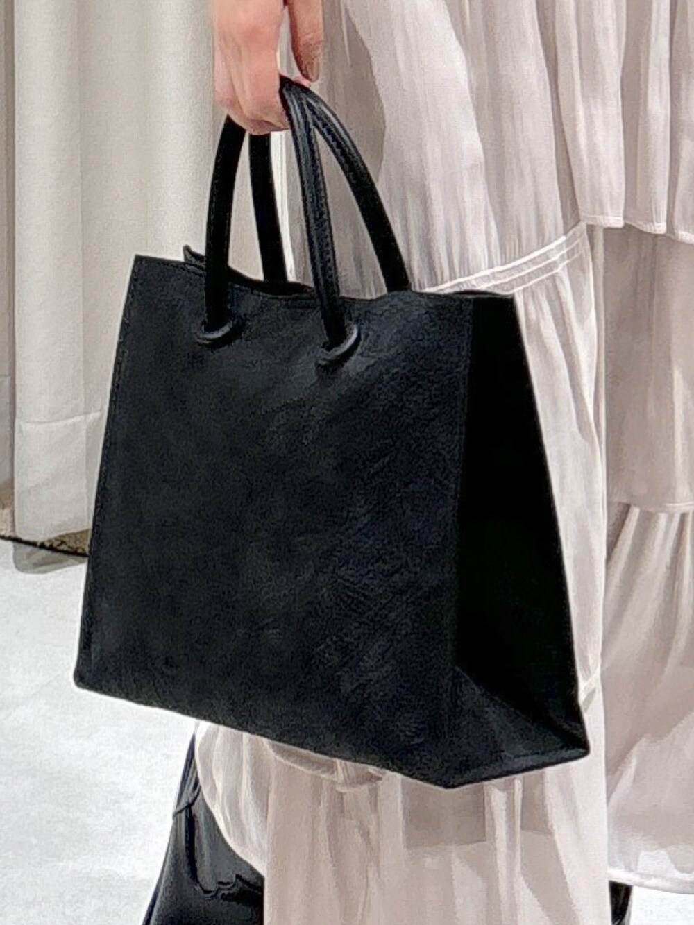 ブラック系のトートバッグ、ホワイト系のスカート、ブラック系のブーツを着用したレディースの冬コーディネートの8枚目の写真