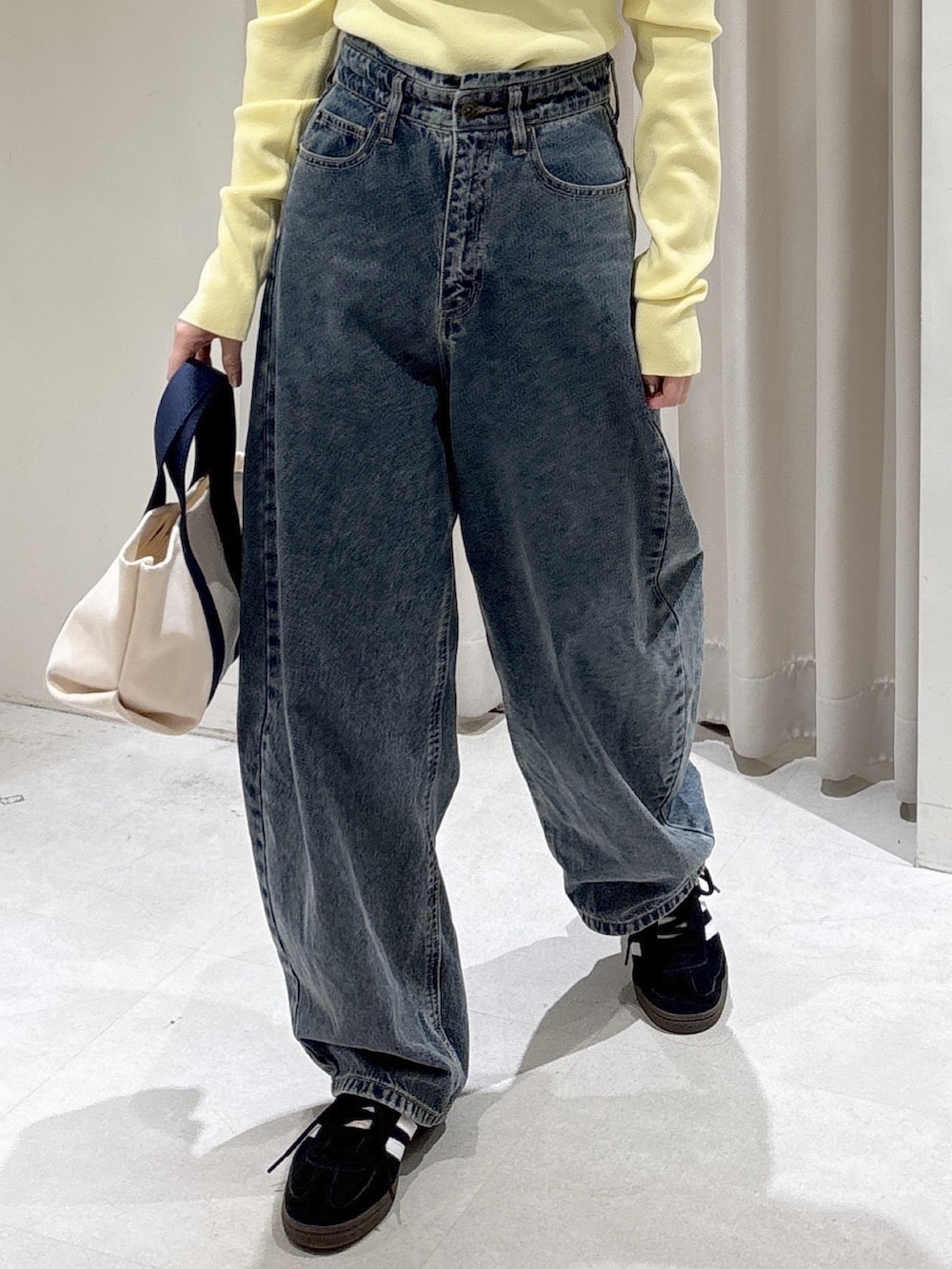 ブラック系のノーカラージャケット、イエロー系のニット/セーター、ブルー系のデニムパンツを着用したレディースの冬コーディネートの6枚目の写真