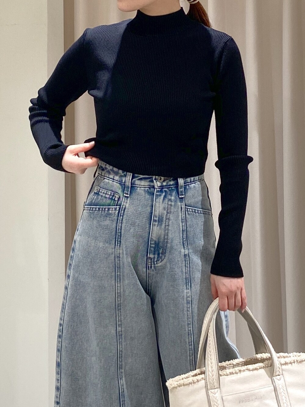 ブラック系のニット/セーター、シルバー系のトートバッグ、ブルー系のデニムパンツを着用したレディースの冬コーディネートの2枚目の写真