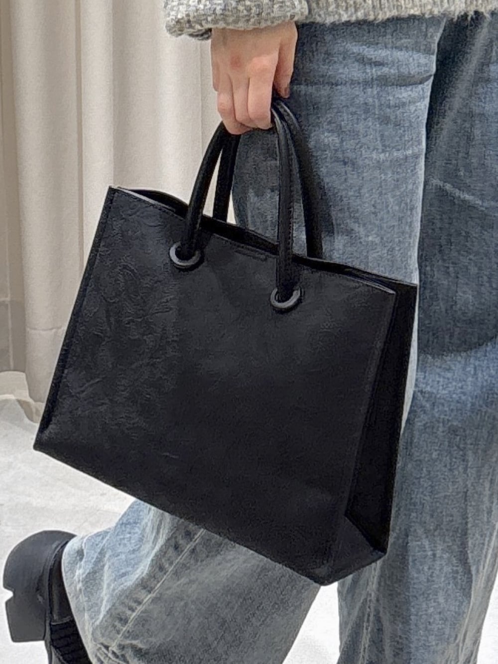 グレー系のニット/セーター、ブラック系のトートバッグ、ブルー系のデニムパンツを着用したレディースの冬コーディネートの5枚目の写真