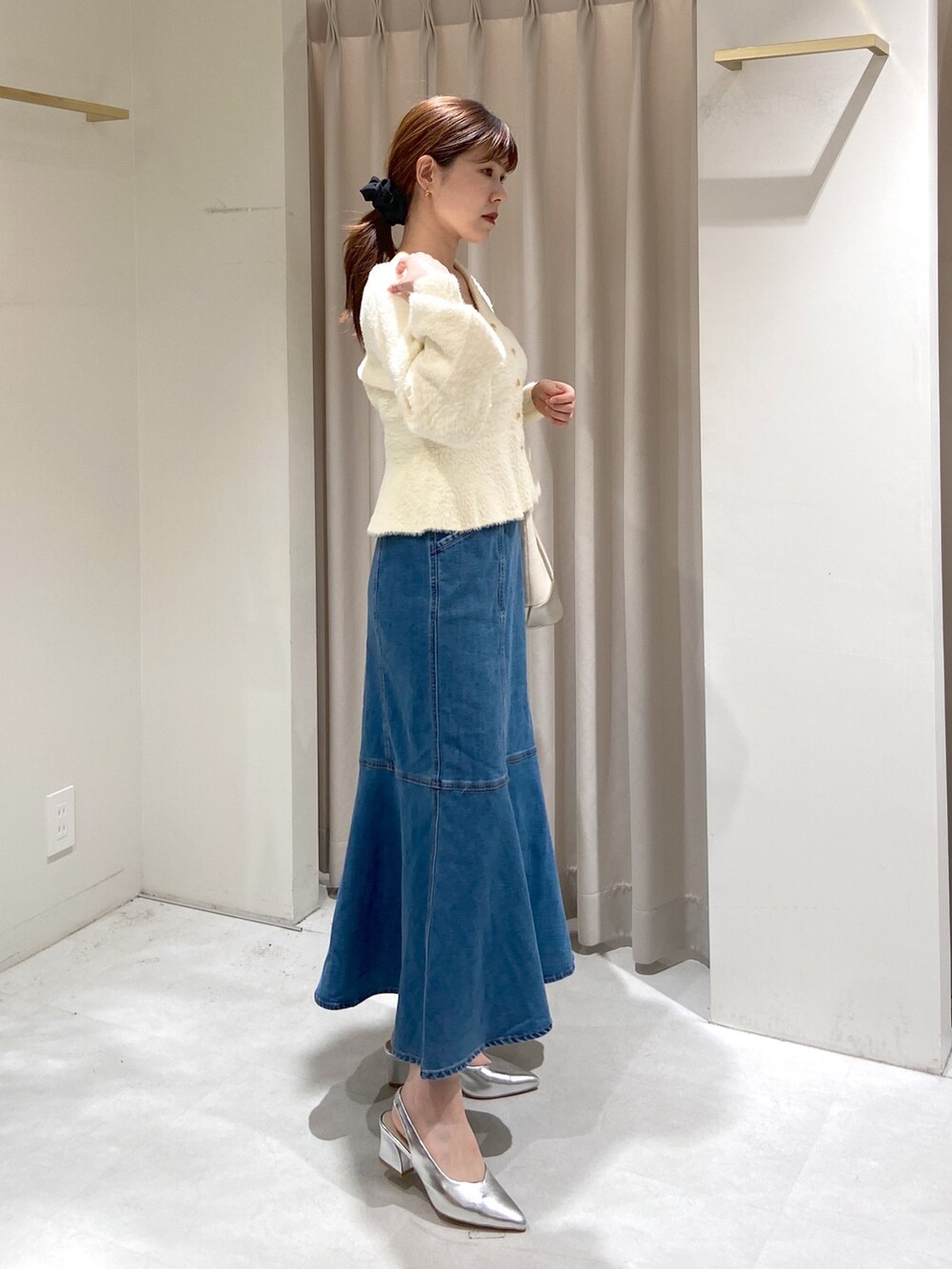 ホワイト系のカーディガン/ボレロ、ブルー系のデニムスカート、シルバー系のパンプスを着用したレディースの冬コーディネートの3枚目の写真