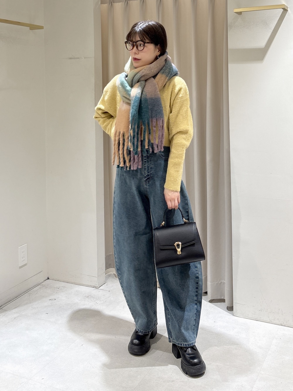 イエロー系のニット/セーター、ブラック系のトートバッグ、ブルー系のデニムパンツを着用したレディースの冬コーディネートの7枚目の写真