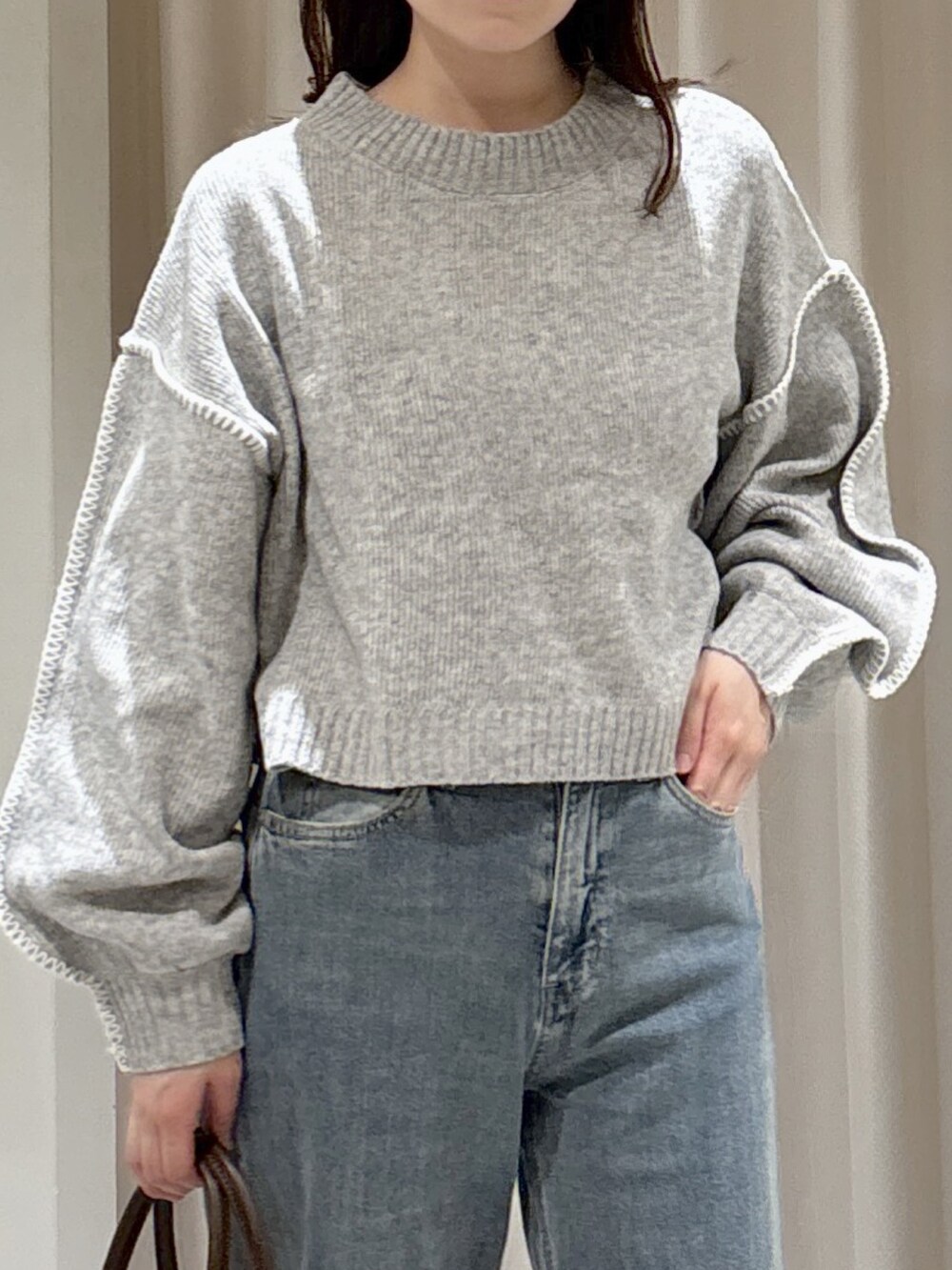 ブラウン系のステンカラーコート、ブルー系のトートバッグ、ブルー系のデニムパンツを着用したレディースの秋コーディネートの6枚目の写真