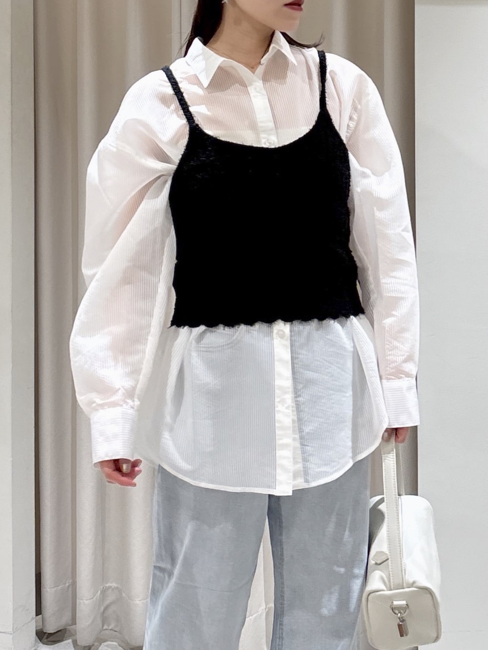 ホワイト系のシャツ/ブラウス、ブラック系のニット/セーター、ブルー系のデニムパンツを着用したレディースの春コーディネートの2枚目の写真