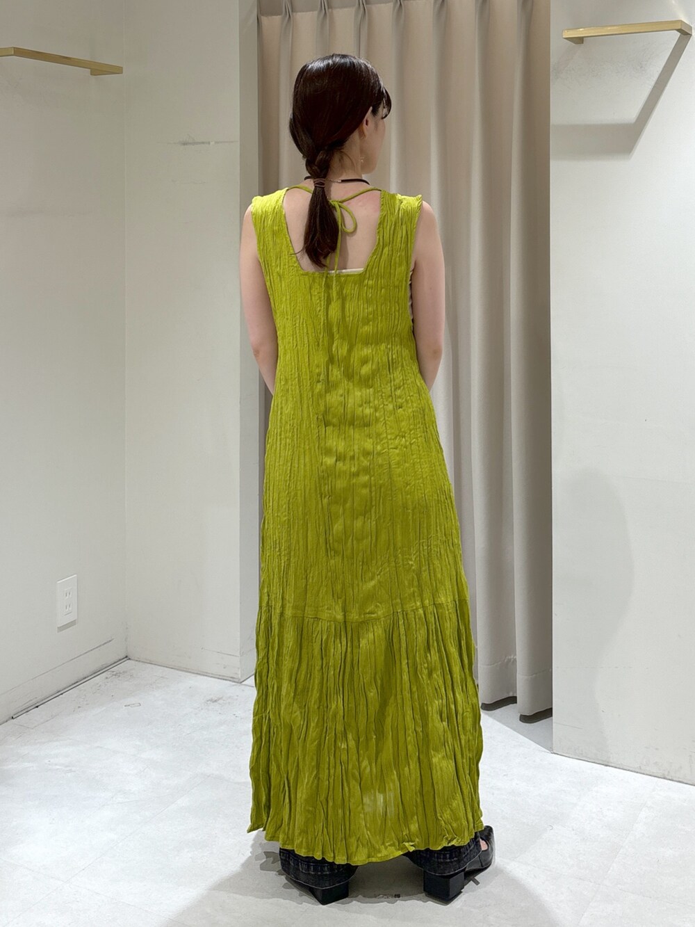 グリーン系のワンピース、ブラウン系のトートバッグ、ブラック系のデニムパンツを着用したレディースの秋コーディネートの6枚目の写真