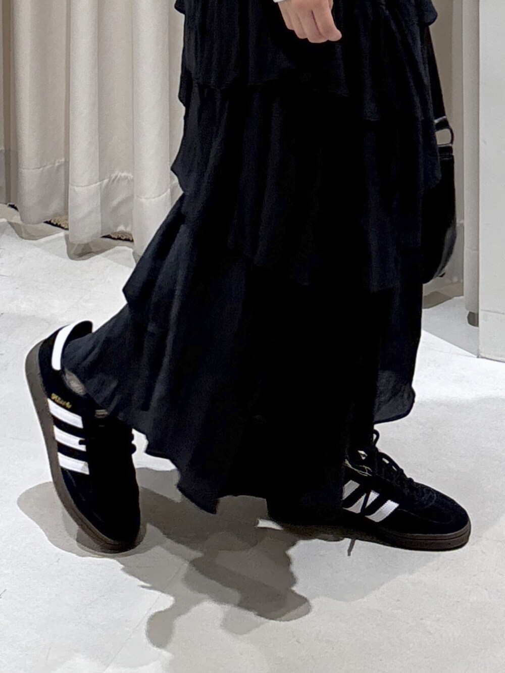 ホワイト系のスウェット、ブラック系のスカート、ブラック系のショルダーバッグを着用したレディースの秋コーディネートの5枚目の写真