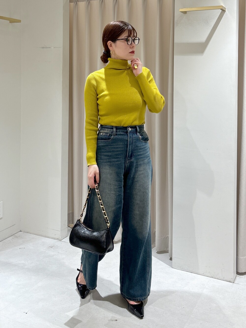 ブラック系のカーディガン/ボレロ、イエロー系のニット/セーター、ブルー系のデニムパンツを着用したレディースの秋コーディネートの3枚目の写真