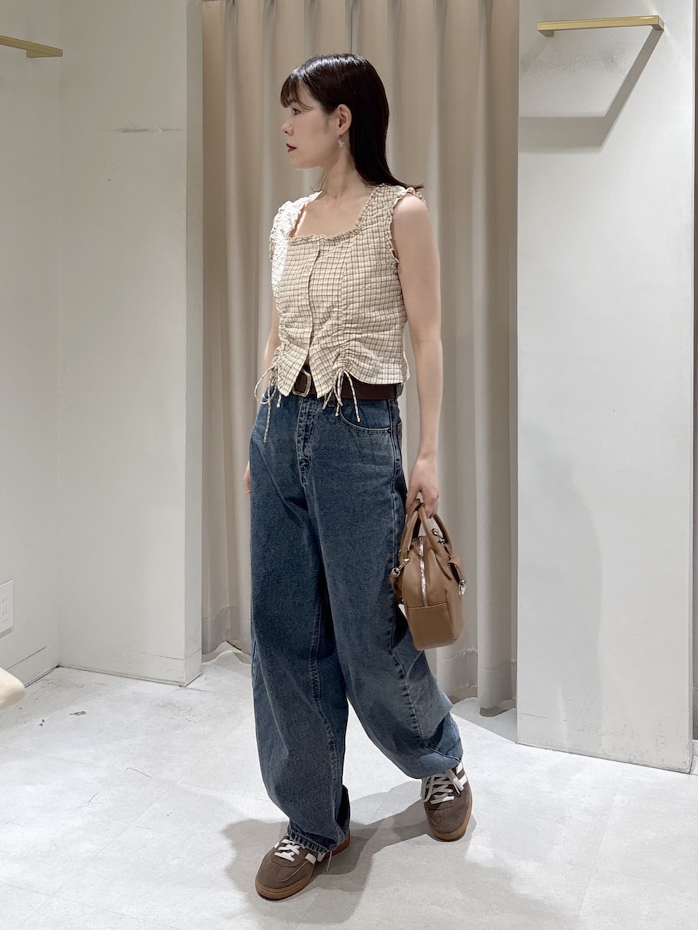 ベージュ系のシャツ/ブラウス、ブルー系のデニムパンツ、ブラウン系のハンドバッグを着用したレディースの春コーディネートの7枚目の写真