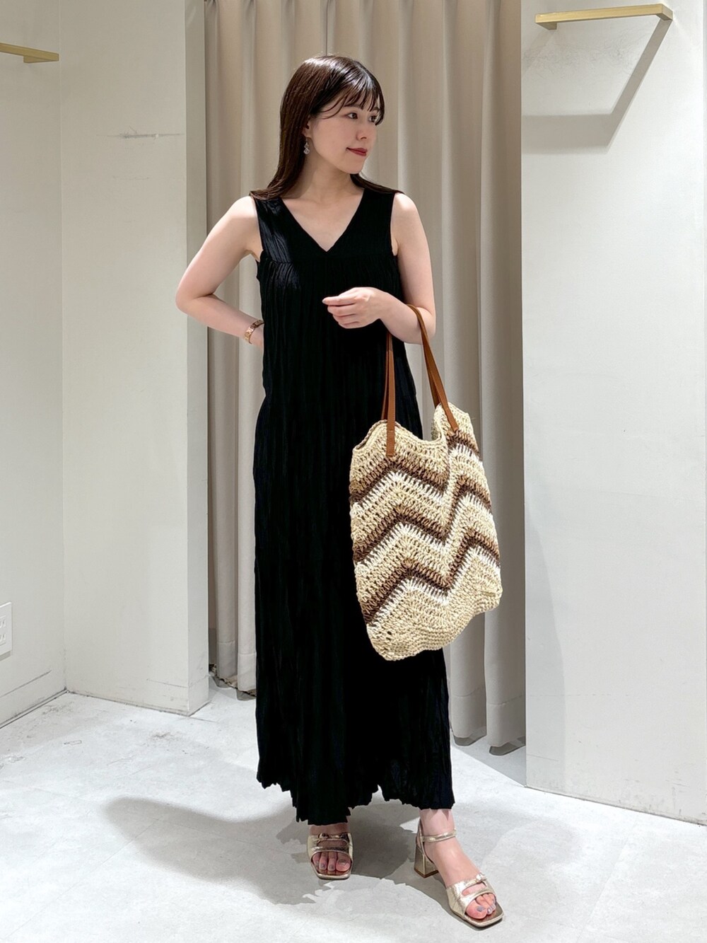 ブラック系のワンピース、ベージュ系のトートバッグ、ゴールド系のサンダルを着用したレディースの夏コーディネートの3枚目の写真