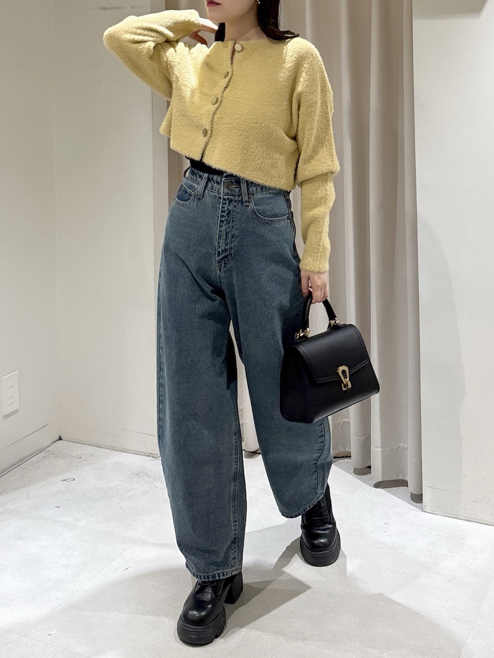 イエロー系のニット/セーター、ブラック系のトートバッグ、ブルー系のデニムパンツを着用したレディースの冬コーディネートの3枚目の写真