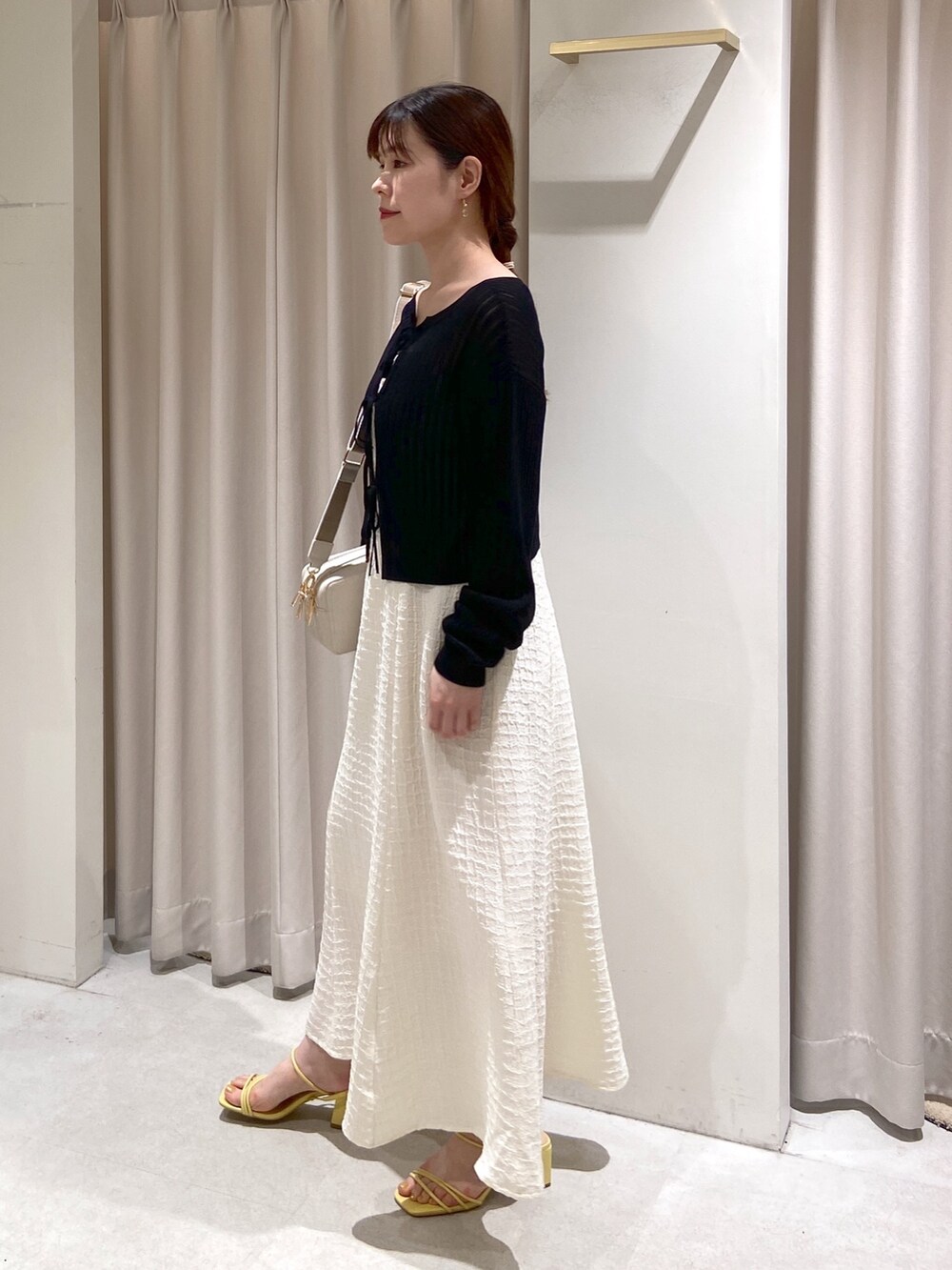 ホワイト系のワンピース、ブラック系のカーディガン/ボレロ、ホワイト系のボディバッグ/ウエストポーチを着用したレディースの春コーディネートの3枚目の写真