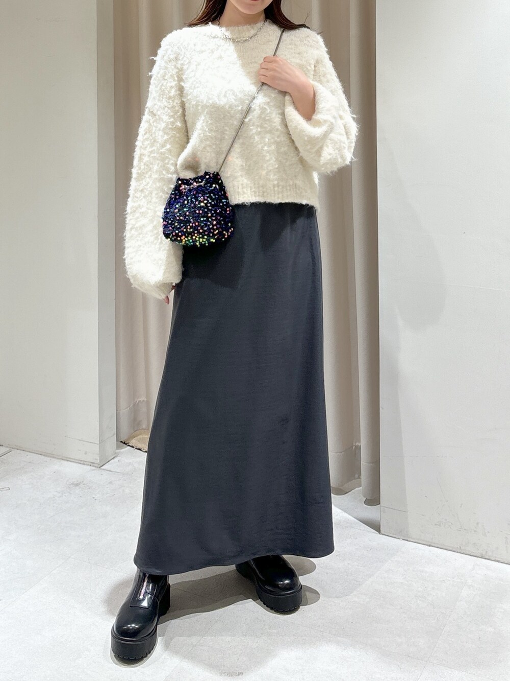 ブラック系のショルダーバッグ、グレー系のスカート、ブラック系のブーツを着用したレディースの冬コーディネートの5枚目の写真