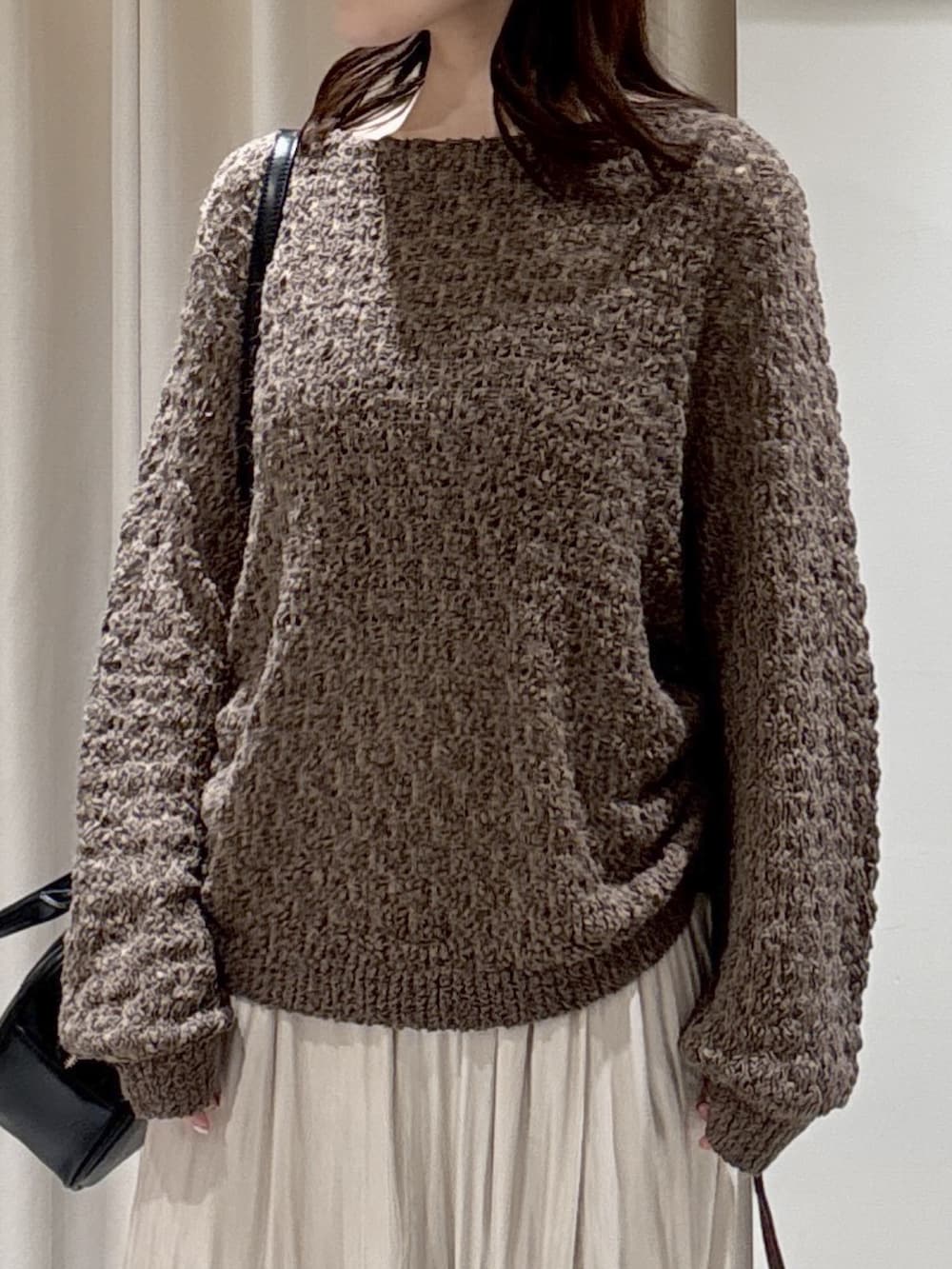 ブラウン系のニット/セーター、ホワイト系のスカート、ブラック系のハンドバッグを着用したレディースの冬コーディネートの3枚目の写真