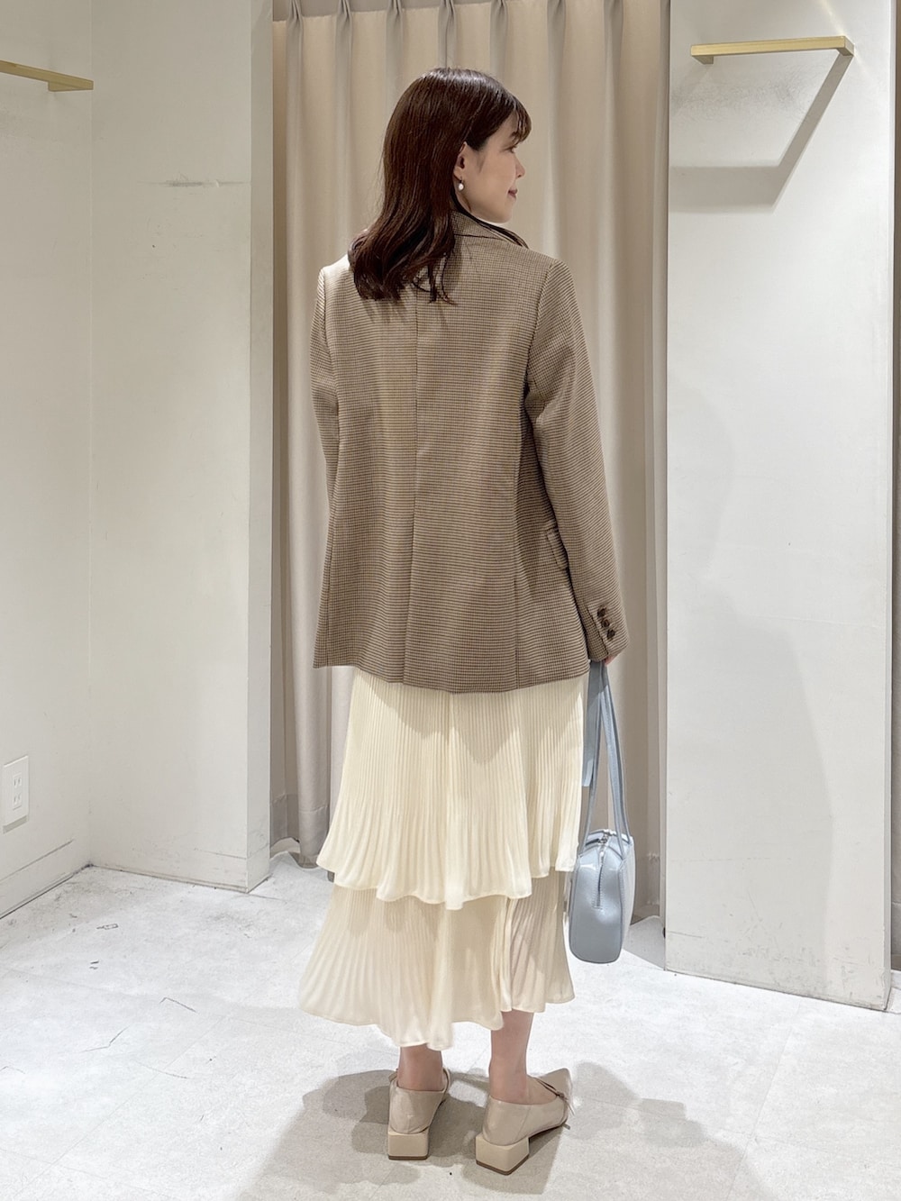 ベージュ系のテーラードジャケット、グレー系のTシャツ/カットソー、ホワイト系のスカートを着用したレディースの春コーディネートの3枚目の写真