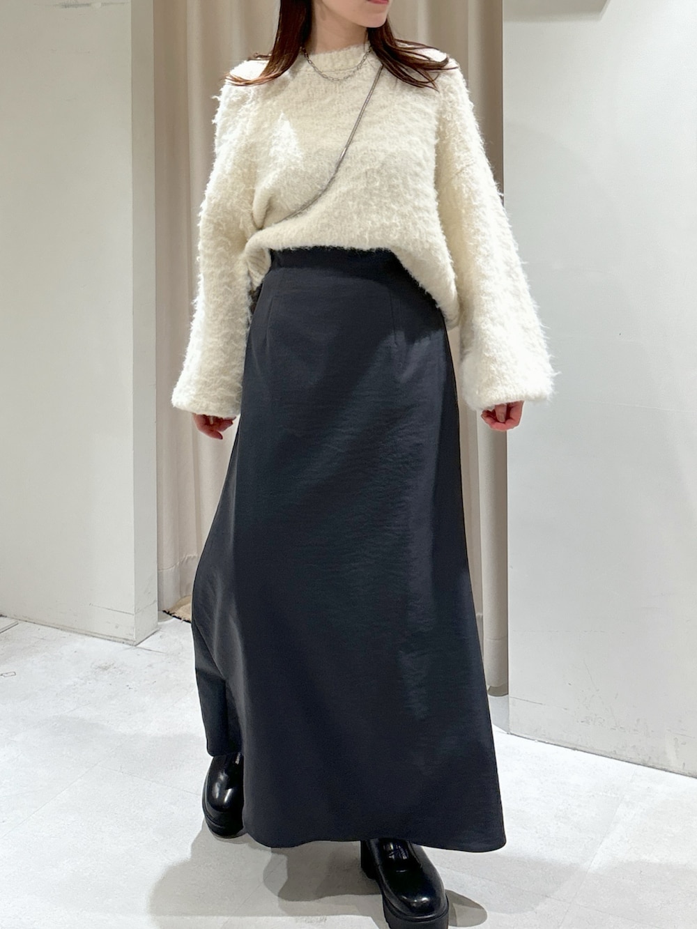 ブラック系のショルダーバッグ、グレー系のスカート、ブラック系のブーツを着用したレディースの冬コーディネートの2枚目の写真