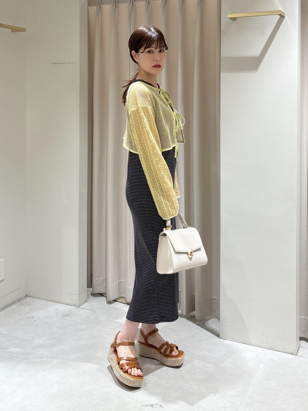 イエロー系のカーディガン/ボレロ、ブラック系のワンピース、ホワイト系のショルダーバッグを着用したレディースの夏コーディネートの2枚目の写真